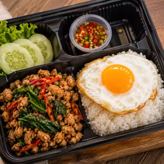 Thai-style lunch box with rice, stir fry and fried egg
